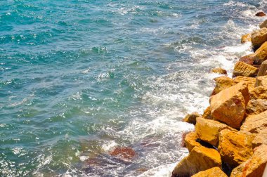 Mavi su dalgaları kayalık bir plajda, Alicante. İspanya
