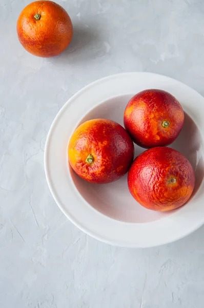 Свежие кровавые апельсины в тарелке на белом каменном фоне . — стоковое фото