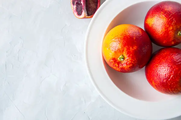 Fresh ripe whole and slices of blood oranges in a plate on a whi — Stock Photo, Image