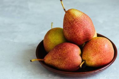 Olgun armut beyaz taş zemin üzerine bir tabak içinde. Tonda. 