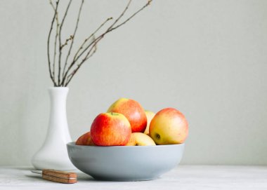 Beyaz zemin üzerinde bir kasede olgun elma. Sonbahar ruh kavramı