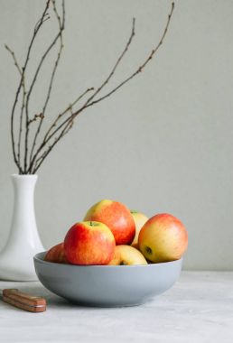 Beyaz zemin üzerinde bir kasede olgun elma. Sonbahar ruh kavramı