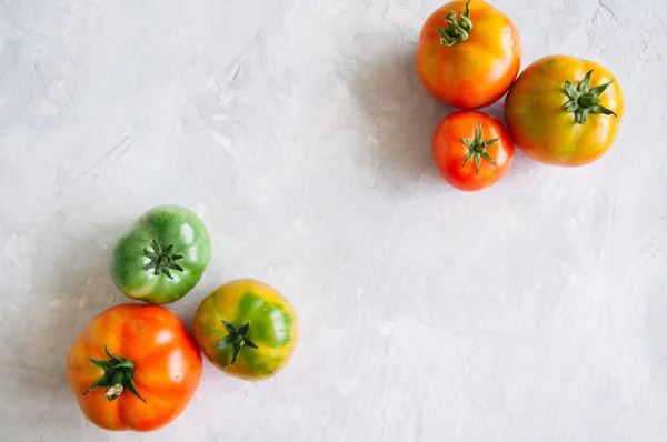 Tamanhos diferentes de tomates frescos coloridos em uma pedra branca atrás — Fotografia de Stock