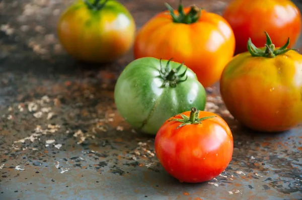 Verschillende maten van kleurrijke verse tomaten op een roestig achtergrond — Stockfoto