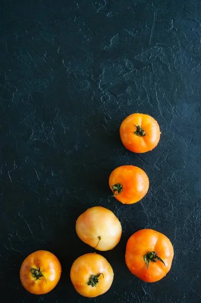 Orange fresh ripe tomatoes on a black stone background. Top view — Stock Photo, Image