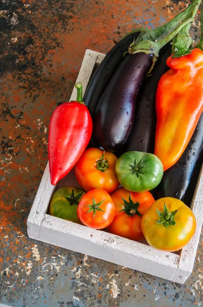 Witte doos met groenten op een roestig achtergrond. Aubergines, bel — Stockfoto