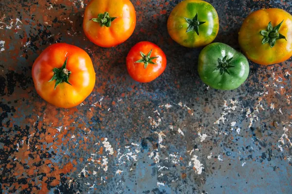 Diferentes tamanhos de tomates frescos coloridos em um fundo enferrujado — Fotografia de Stock