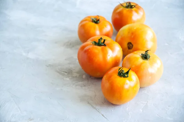 Oranje verse rijpe tomaten op een witte achtergrond van de stenen. Bovenaanzicht — Stockfoto