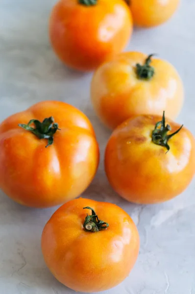 Laranja tomates maduros frescos em um fundo de pedra branca. Fechar — Fotografia de Stock