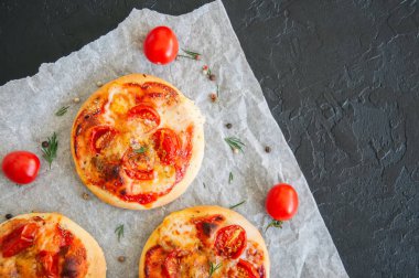 Mini pizza margheritas üzerinde bir parşömen kağıt üzerine siyah bir taş ba
