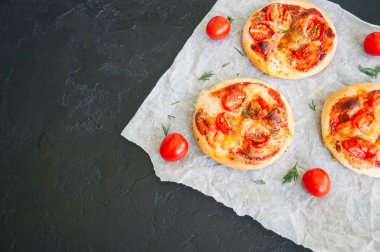 Mini pizza margheritas üzerinde bir parşömen kağıt üzerine siyah bir taş ba