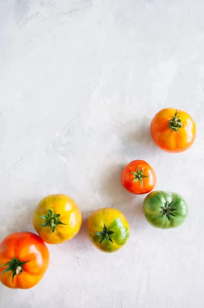 Diferentes tamanhos e cores de tomates frescos em uma pedra branca ba — Fotografia de Stock