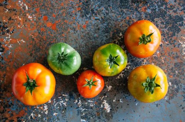 Diferentes tamanhos e cores de tomates frescos em um backgrou enferrujado — Fotografia de Stock