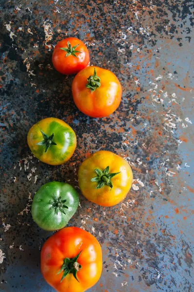 Diferentes tamanhos e cores de tomates frescos em um backgrou enferrujado — Fotografia de Stock