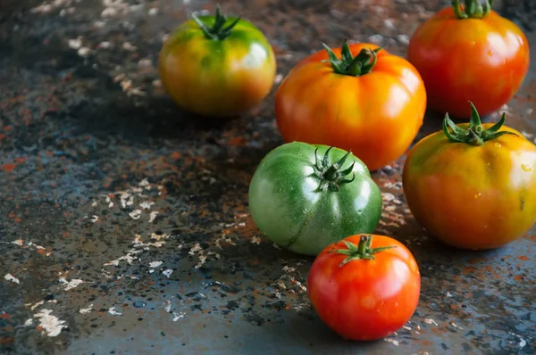 Різні розміри і кольори свіжих помідорів на іржавому фоні — стокове фото