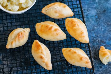 Küçük bir tel raf içinde patates poğaçası (el turta) püresi. Mavi sto