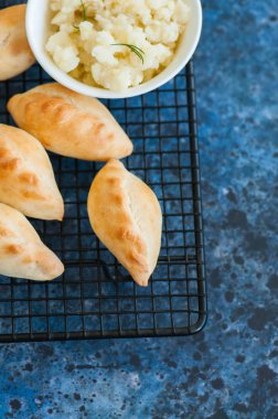 Küçük bir tel raf içinde patates poğaçası (el turta) püresi. Mavi sto