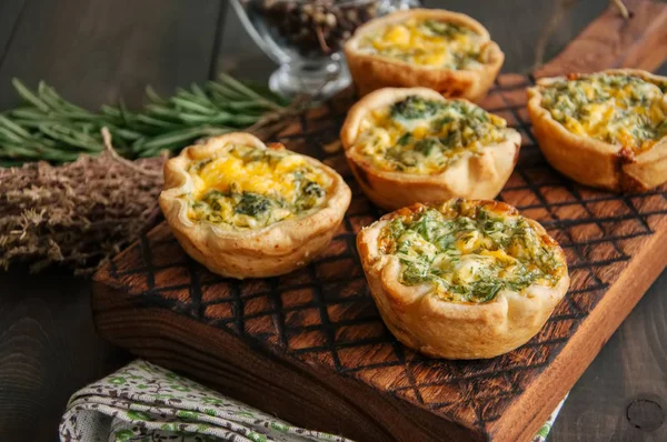 Mini quiches salgados (tortas) em uma placa de madeira. Tortas de massa folhosas . — Fotografia de Stock