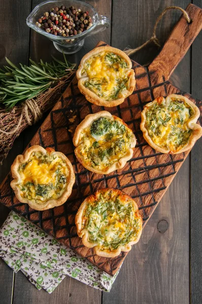 Savory mini quiches (tarts) on a wooden board. Flaky dough pies. — Stock Photo, Image
