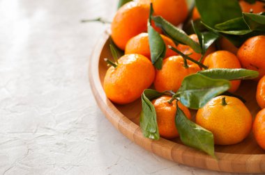 Taze ve sulu mandalina beyaz bir taş yapraklarda ile tabak