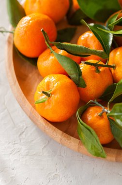 Taze ve sulu mandalina beyaz bir taş yapraklarda ile tabak