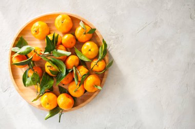 Taze ve sulu mandalina beyaz bir taş yapraklarda ile tabak