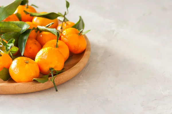 Plate of fresh and juicy tangerines with leaves on a white stone — Stock Photo, Image