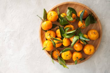 Taze ve sulu mandalina beyaz bir taş yapraklarda ile tabak