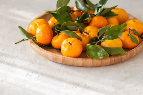 Taze ve sulu mandalina beyaz bir taş yapraklarda ile tabak