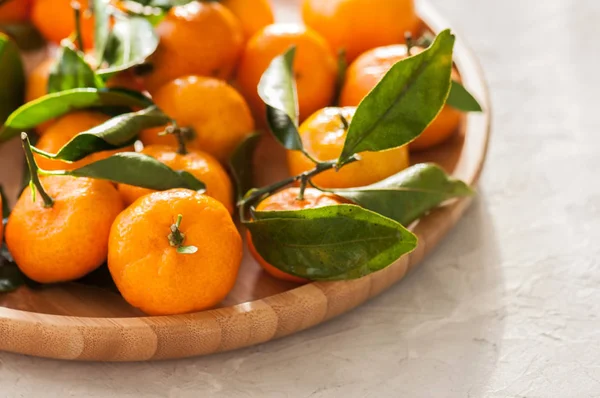 Taze ve sulu mandalina beyaz bir taş yapraklarda ile tabak