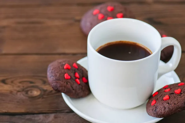 Uma xícara de café preto e biscoitos de chocolate em um pano de fundo de madeira — Fotografia de Stock