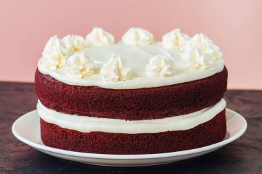Kırmızı kadife kek krem peynir beyaz bir plaka üzerinde buzlanma ile