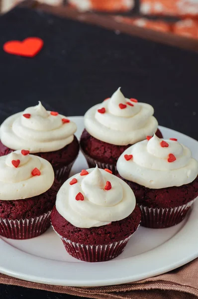 Magdalenas de terciopelo rojo con glaseado de queso crema en un plato blanco —  Fotos de Stock