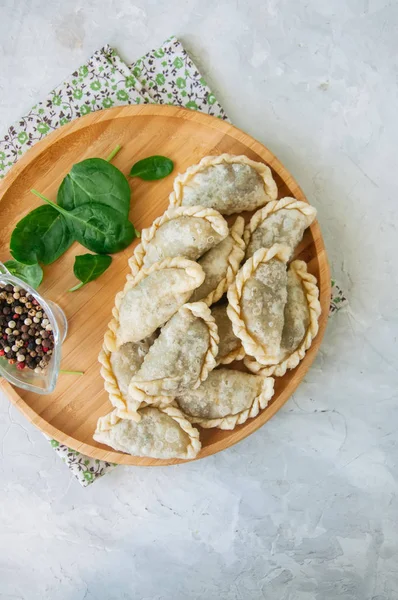 Gebratene pikante Pasteten - Handpastete mit Spinat auf weißem Backblech — Stockfoto