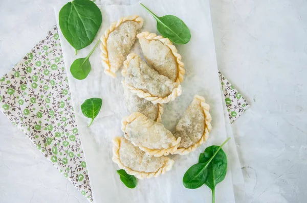 Gebratene pikante Pasteten - Handpastete mit Spinat auf weißem Backblech — Stockfoto