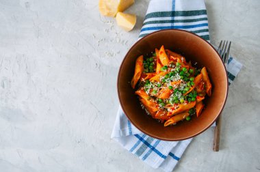 Bir plaka üzerinde beyaz bir st domates sosu ve yeşil bezelye penne makarna