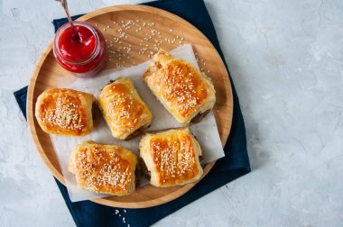 Sığır eti ve caramelised soğan sosis rolls ile ahşap bir plaka üzerinde 