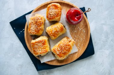 Sığır eti ve caramelised soğan sosis rolls ile ahşap bir plaka üzerinde 