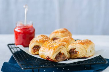 Sığır eti ve caramelised soğan sosis rolls ile ahşap bir plaka üzerinde 