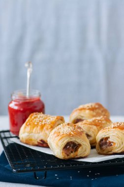Sığır eti ve caramelised soğan sosis rolls ile ahşap bir plaka üzerinde 