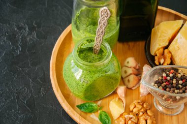 Fesleğen ceviz pesto hammaddelerini ahşap bir pla üzerinde bir kavanoza