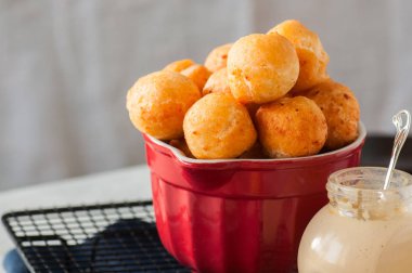 Küçük süzme peynir çörek (castgnole) kırmızı bir kasede servis.