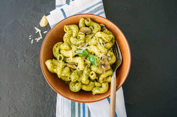 Pasta italiana con pesto al basilico ed erbe aromatiche in un piatto su una s nera — Foto Stock