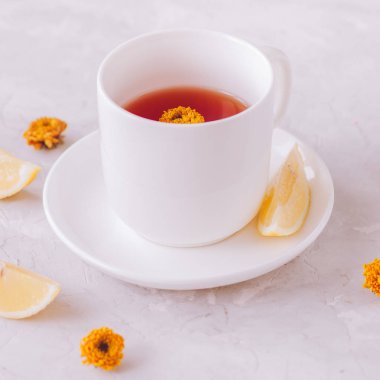 Bir bardak limonlu beyaz taş zemin üzerine çiçek çay. Stil