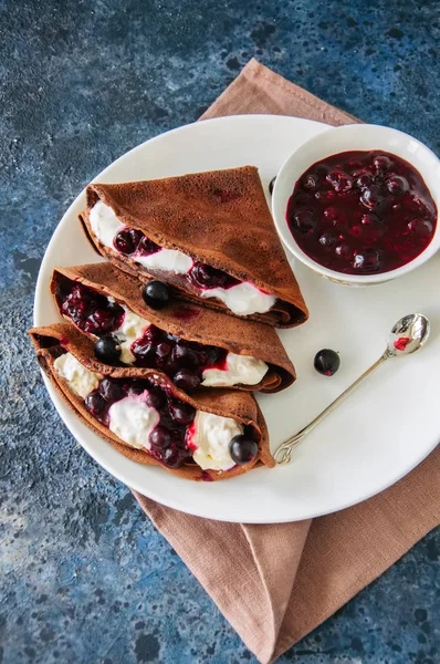 Chocolate crepes (blinis) with sour cream sauce and black curran