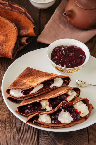 Chocolate crepes (blinis) with sour cream and black currant sauc