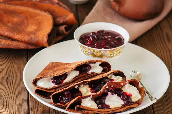 Chocolate crepes (blinis) with sour cream and black currant sauc