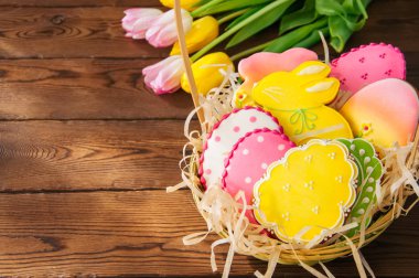 Ahşap ba üzerinde sepetteki renkli Paskalya bunny ve yumurta kurabiye