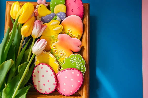 Bunte Osterhasen und Eierplätzchen in einem Korb auf einem Holztisch — Stockfoto