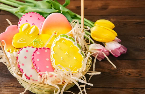 Bunte Osterhasen und Eierplätzchen in einem Korb auf einem Holztisch — Stockfoto